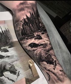 a man's arm with a bear and water scene on it