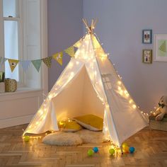 a teepee tent with lights on it in a child's playroom or bedroom