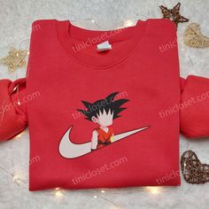 Son Goku Kid Nike Embroidered Shirt, Dragon Ball Embroidered Sweatshirt, Anime Hoodie for Fan Welcome to Tinicloset, a treasure trove of enchanting fashion that invites you to embrace your love for anime through our meticulously crafted custom embroidered shirts, embroidered sweatshirts, t-shirts, and hoodies. Our store is more than just a shopping destination; it’s a realm where imagination and style intertwine, where each stitch tells a story. At the heart of our collection lies the icon Anime Cotton Sweatshirt For Fan Merchandise, Anime Cotton Sweatshirt For Fans, Anime Cotton Sweatshirt With Crew Neck, Red Casual Sweatshirt With Custom Embroidery, Red Hooded Hoodie With Embroidered Graphics, Anime Cotton Hoodie Sweatshirt, Anime Style Cotton Hoodie Sweatshirt, Embroidered Red Hoodie For Streetwear, Red Embroidered Hoodie For Streetwear