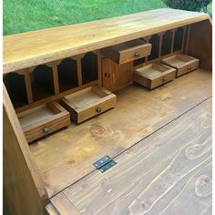 a wooden table with drawers on it in the middle of some grass and wood planks