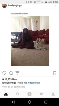 a woman sitting on the floor next to a child wearing a blanket and holding a laptop