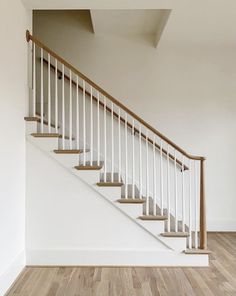 a white staircase with wooden handrails in an empty room