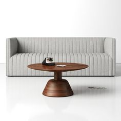 a couch sitting next to a coffee table on top of a white floor with a wooden base