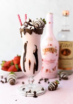 an ice cream sundae with chocolate and strawberries on the table next to a bottle of booze