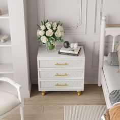 a bedroom with white furniture and flowers on the nightstand