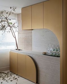 a kitchen with marble counter tops and wooden cabinetry next to a tree in the corner