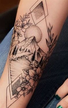 a woman's arm with flowers and mountains on it