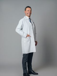 a man in a white lab coat is standing with his hands on his hips and smiling