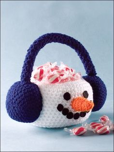 a crocheted snowman with headphones on and candy in the bag next to it