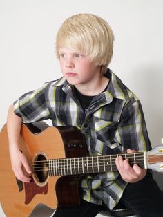 a young boy is playing an acoustic guitar