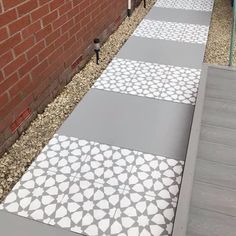 the walkway is painted with white and gray designs on it, along with brick walls