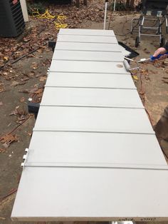 a man is working on a large white piece of wood that has been placed in the ground