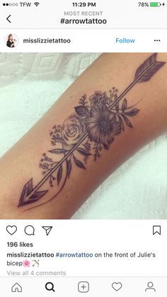 a woman's arm with an arrow and flowers tattoo on it