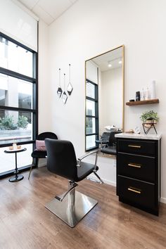 a salon chair sitting in front of a mirror on top of a hard wood floor