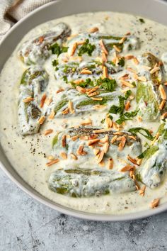 a white bowl filled with broccoli covered in cream sauce and topped with toasted almonds