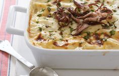 a casserole dish with meat and cheese in it on a striped table cloth