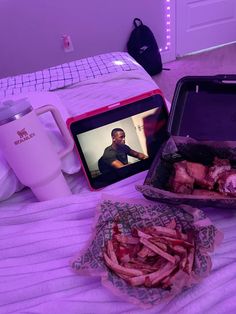 a bed with two trays of food on it and a video screen in the middle