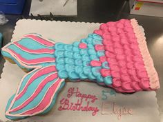 a decorated birthday cake with pink and blue icing on it's side, in the shape of a fish