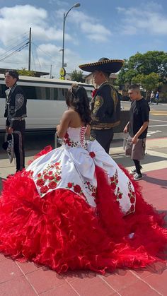 a woman in a red and white dress is walking down the street with other people