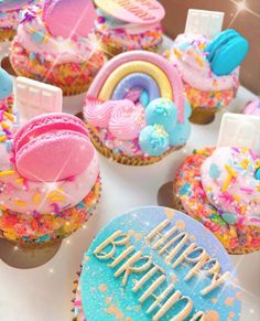 birthday cupcakes with rainbow frosting and sprinkles are on display