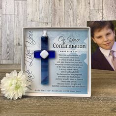 a blue cross with a white flower in front of it on a wooden table next to a card