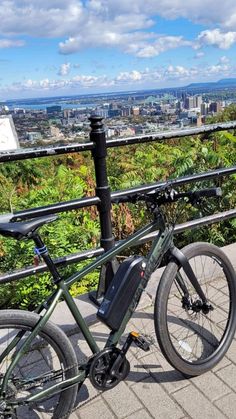 a bicycle parked on the side of a metal railing overlooking a cityscape with tall buildings in the background