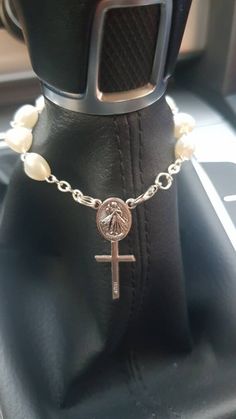 a car steering wheel with a cross and pearl beads on the chain attached to it