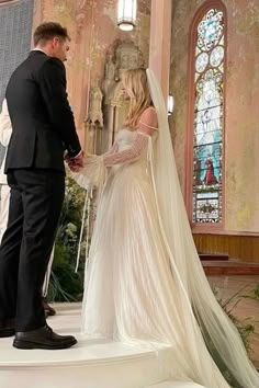 a man and woman standing in front of a church alter with the bride wearing a long veil