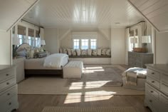 an attic bedroom with white walls and wood flooring, large bed in the center