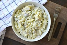 a white bowl filled with macaroni and cheese on top of a wooden cutting board