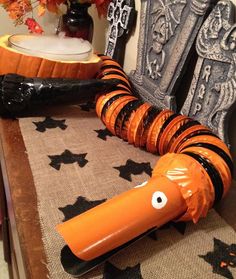 an orange and black striped snake sitting on top of a wooden chair next to a vase filled with flowers