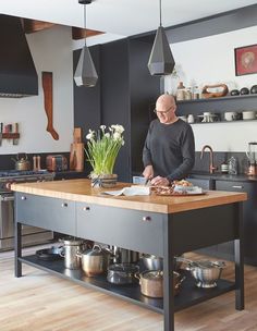 a man standing at a kitchen island with pots and pans on it