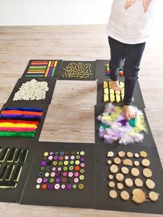 a child standing on top of a black mat covered in lots of crafting supplies