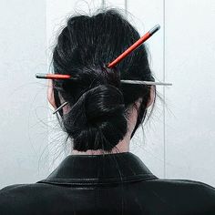 the back of a woman's head with scissors in her hair and two needles sticking out of it