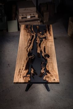 a table made out of wood and metal legs with black paint on the top, in a dark room