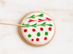 a decorated cookie with green and red decorations on it, next to a toothpick