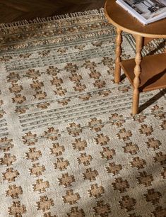 a table with a magazine on top of it next to a rug that has been placed on the floor