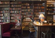 a man sitting at a table in front of a bookshelf filled with lots of books