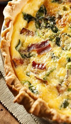 a quiche with bacon, spinach and cheese in a pie pan on a table