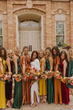 a group of women standing next to each other in front of a building with flowers