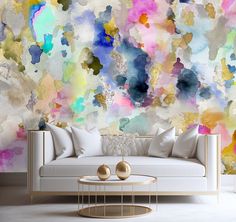 a living room scene with focus on the couch and wallpaper that has colorful paint splatters all over it