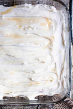 a glass dish filled with white frosting on top of a wooden table