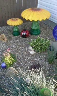 a garden with plants, rocks and ladybug figurines in the gravel