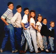 a group of children standing next to each other in front of a blue background,