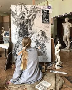 a woman sitting in front of a drawing on a easel with her hair pulled back