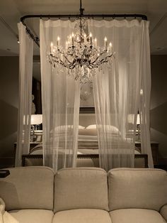 a white couch sitting under a chandelier next to a bed