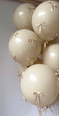 a bunch of white balloons with bows on them