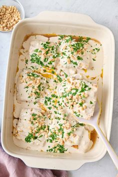 a casserole dish with white sauce and green garnish