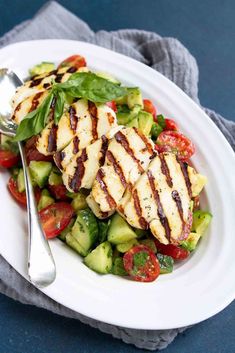 grilled chicken, cucumber and tomato salad on a white plate with a fork