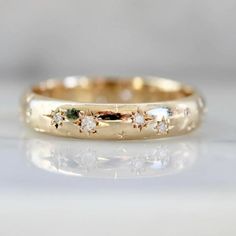 a yellow gold wedding band with five diamonds on it's side, sitting on a white surface